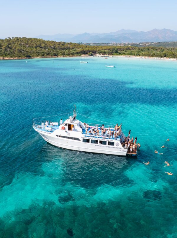 Swim stop in the Protected Marine Area of Tavolara with the motorboat anchored near the crystal-clear coast.