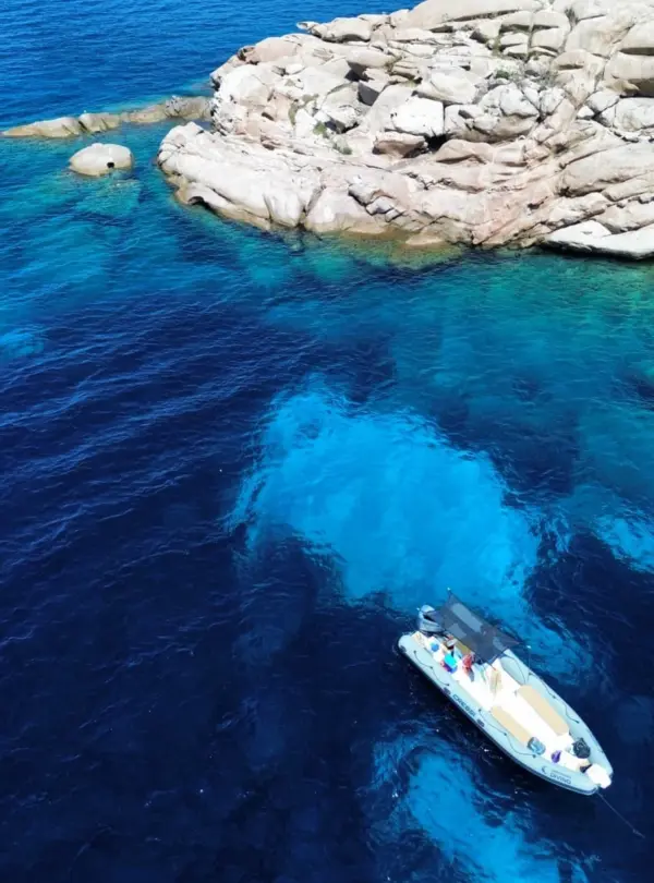 Gommone per snorkeling a Tavolara con mare cristallino e scogliere sullo sfondo